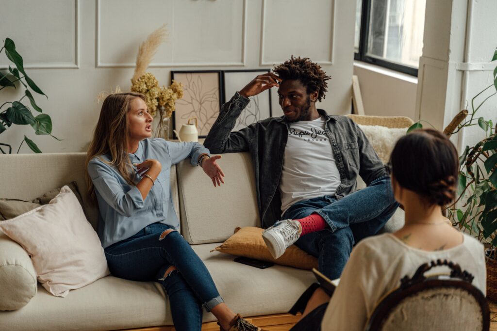 Couple talking on couch across from Therapist in chair.